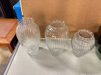 Three clear ribbed glass vases side by side showing relative sizes and ribbed pattern