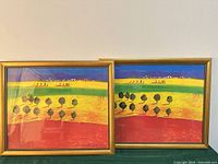 Front view of two identical landscape prints in gold metal frames