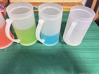 Front view of five frosted plastic mugs showing green, blue and clear variants