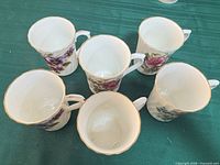 Top view of six floral bone china mugs showing interiors and gold rims