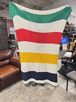 Full view of striped wool-blend throw blanket held up to show colors and size