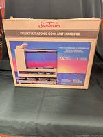 Retail box showing Sunbeam Deluxe Ultrasonic Cool Mist Humidifier graphics and specifications