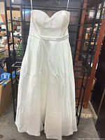 Front view of strapless white satin wedding dress on hanger