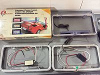 Retail box and three clear neon license plate frames displayed