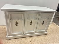 Front view showing cabinet, paneled doors, brass pulls