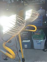 Front view showing both halogen heads with wire guards and yellow stand