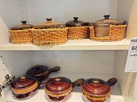 Four natural-tone casseroles in wicker holders and four brown swirl casseroles on shelf