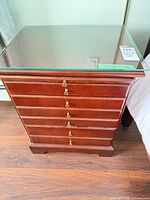 Front view of one nightstand showing drawers, glass top