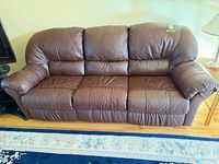 Front view of brown leather 3-seat sofa on hardwood floor