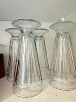 four clear fluted tall glasses upside down on shelf