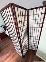 Angle view of one room divider showing dark brown wood lattice and white panels
