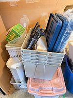 Stack of grey totes, lids, dolly, pink tote, white bin in view