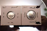 Both coins in cardboard holders, mackerel 10¢ left, bobcat 25¢ right