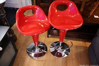 Front view of both red bar stools with chrome bases