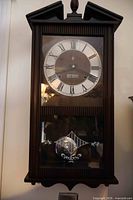 Front view of wooden wall clock showing full case and dial