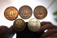 Five coins arranged, three halfpennies top, threepence and 100-yen bottom