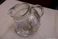 Full view of clear ribbed ball pitcher with handle and spout