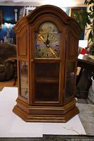 Front view of oak curio cabinet clock showing full case and glass panels