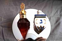 Full view of perfume bottle and ceramic dreidel on mirror