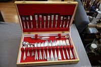 Open chest showing full 51-piece silverplate flatware service arranged in red felt interior