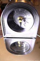 Front view of pewter desk clock showing Roman numeral dial and hands