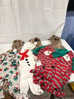 Five of the outfits laid out: two reindeer suits, snowman sleeper, striped Santa sleeper, holiday print sleeper