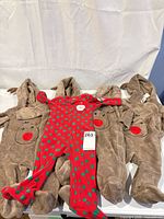 Four brown reindeer bunting suits and one red polka dot sleeper laid out