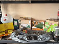 Shelf view showing deflated convertible airbed, Primus lantern, Primus stove box, additional camping items