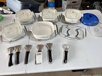 Overview of casseroles, trays, handles and lids displayed on table