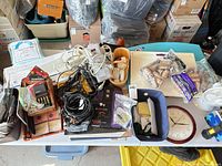 Overview of mixed office supplies on table including cords, batteries, clock, organizer trays