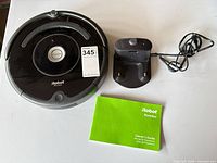Roomba vacuum, charging dock, Owner’s Guide booklet displayed on table