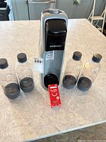 Front view of SodaStream machine with four bottles, bubly syrup pack