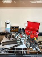 Overview of lot on shelf; drills, jigsaw, grease gun, oil can, toolbox, binoculars, Moen package