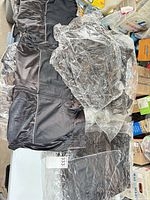 Pile of packaged black full-zip sleeveless vests