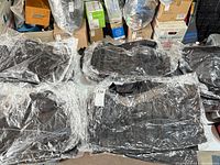 Multiple sealed black vests stacked on table