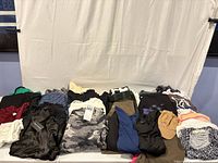 Overview of assorted clothing and two hats on table