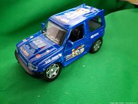 Front left view of blue toy SUV with decals