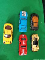 All five Hot Wheels cars arranged on green cloth