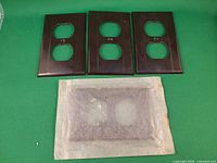 Front view of four brown duplex outlet covers, three exposed, one wrapped