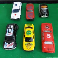 Six die-cast toy cars grouped on green surface