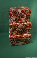 Stacked view of three holiday-print cardboard boxes