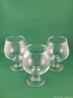 Three clear glass brandy snifters upright