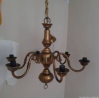 Overall view of brass six-arm chandelier hanging from chain