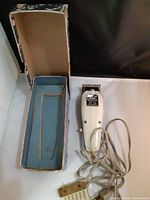 Clipper, power cord, guide comb, open box interior visible