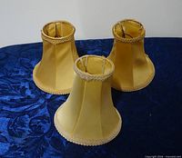 Three gold fabric chandelier shades upright showing exterior
