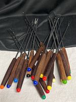 Pile of fondue forks showing teak handles and colored tips