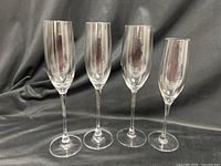 Four Lenox crystal champagne flutes standing upright on dark backdrop