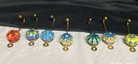 Seven ceramic-knob brass hooks lined up
