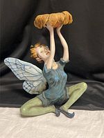 Full view of figurine seated with wings and bowl
