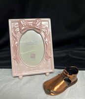 Porcelain frame and copper baby shoe side by side